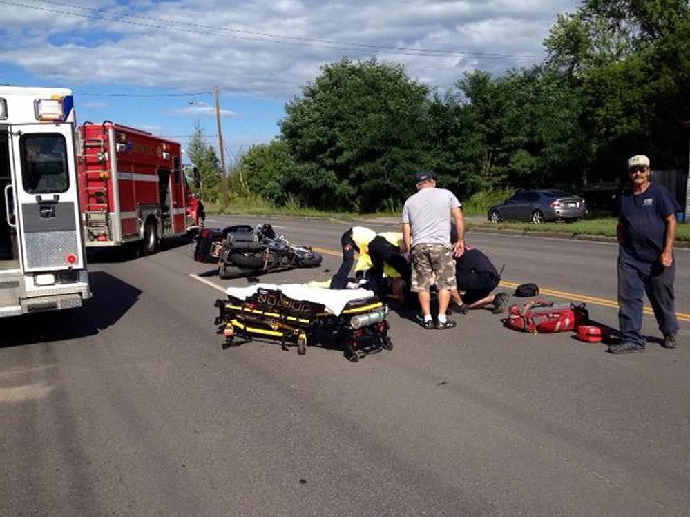 Emergency responders help a motorcyclist who was injured in a collision with a Jeep on College Avenue Thursday afternoon in Waterville. Staff photo by Amy Calder