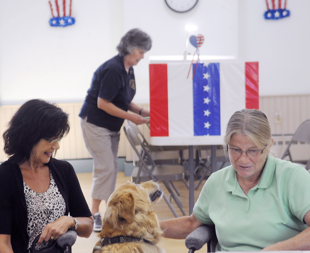 Grace Keene, center, votes Tuesday at the Readfield town hall as her dog, Murphy, waits with clerks Marilyn Palmer, left, and Karen Peterson.