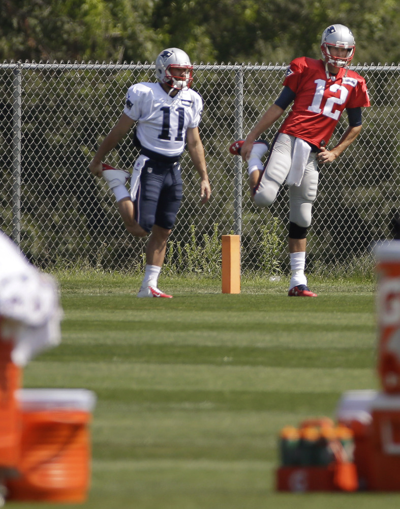New England Patriots quarterback Tom Brady (12) and wide receiver Julian Edelman (11) stretch before practice begins at the team’s facility Tuesdayin Foxborough, Mass.