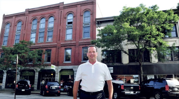 Bill Mitchell stands between the two buildings he now owns on Common Street in Waterville, which he plans to fix up and lease for a restaurant, businesses and office space.