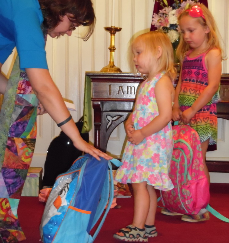 Winthrop Congregational Church Pastor Chrissy Cataldo blesses Alice Lazure’s back pack while sister Gabby waits in the background. This is the second year Cataldo has blessed student and teachers’ backpacks, laptops and lesson plans the Sunday before school returns to session.