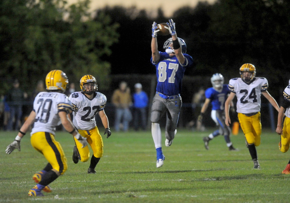 Staff file photo by Michael G. Seamans 
 Lawrence High School receiver Seth Powers (87) makes a catch between Mt. Blue defenders during a game last September in Farmington. Powers and the Bulldogs open their season Friday night at Skowhegan.