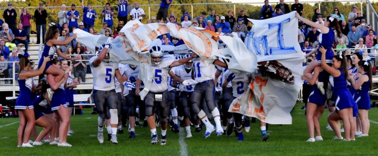 Staff photo by David Leaming 
 Members of the Lawrence football team burst through a banner before a Pine Tree Conference Class B game Friday night against host Skowhegan.