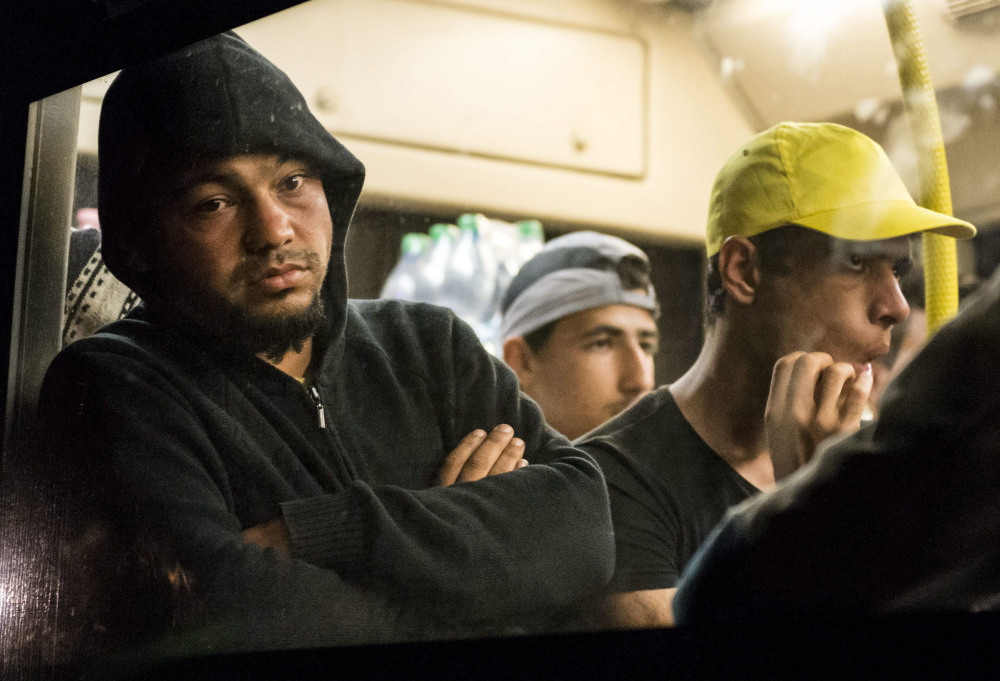Migrants sit in a bus before its departure in Zsambek, west of Budapest, Hungary, early Saturday after some 1,200 migrants marched from Keleti Railway Station in Budapest to this village.