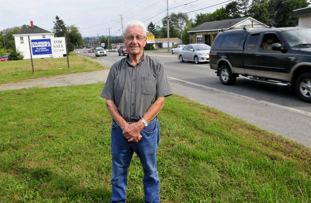 Leland Bard stands at his lot Thursday as traffic passes on Kennedy Memorial Drive in Waterville. Bard is having difficulty selling the land because of zoning restrictions.