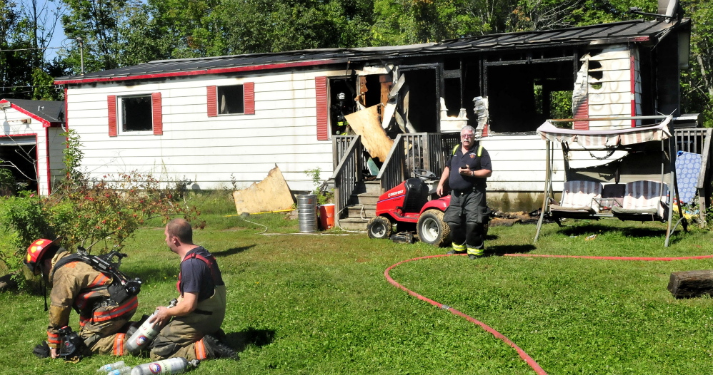 Skowhegan firefighter Linwood Corson walks out of the remains of the Main Street, Canaan, home that burned Sunday, as firefighters replace oxygen tanks at the scene where fire destroyed the home on Main Street in Canaan on Sunday.