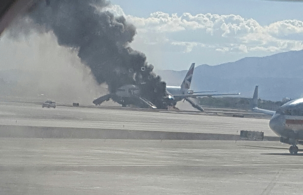In this photo taken from the view of a plane window, smoke billows out from a plane that caught fire at McCarren International Airport, Tuesday in Las Vegas.