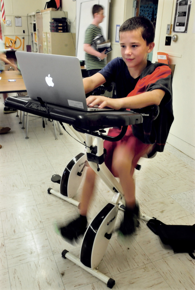 China Middle School student James Hardy pedals a bike while working on his laptop during math class on Wednesday. Hardy said he enjoys using the bike for both exercise and relaxation.