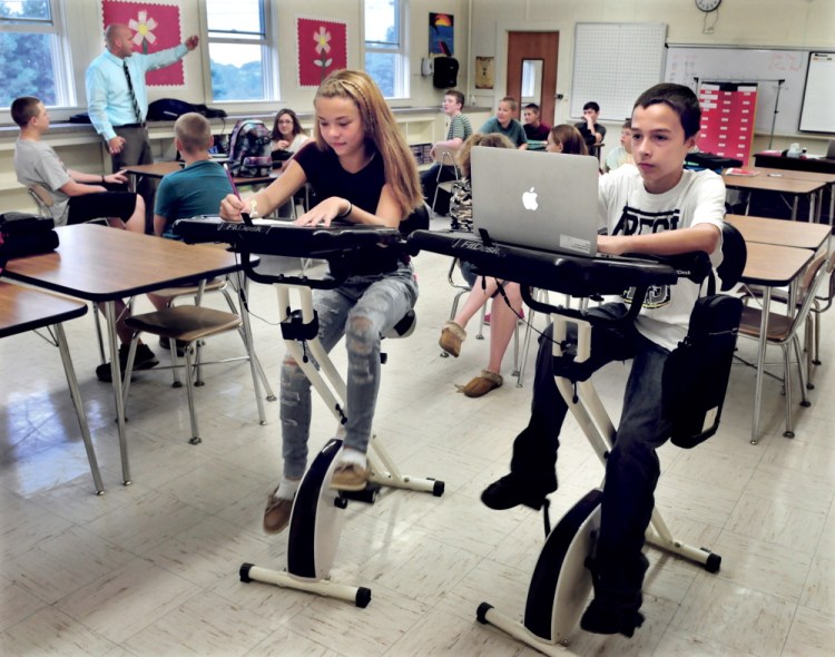 China Middle School eight grade students Morgan Presby and Colby Marston study and pedal at thier bike desks as teacher Josh Lambert leads the class on Wednesday.