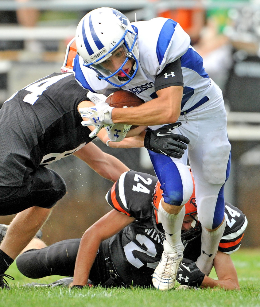 Madison running back Matt Curtis, front, is hit by Winslow’s Justin Martin, left, during a game last season in Winslow.