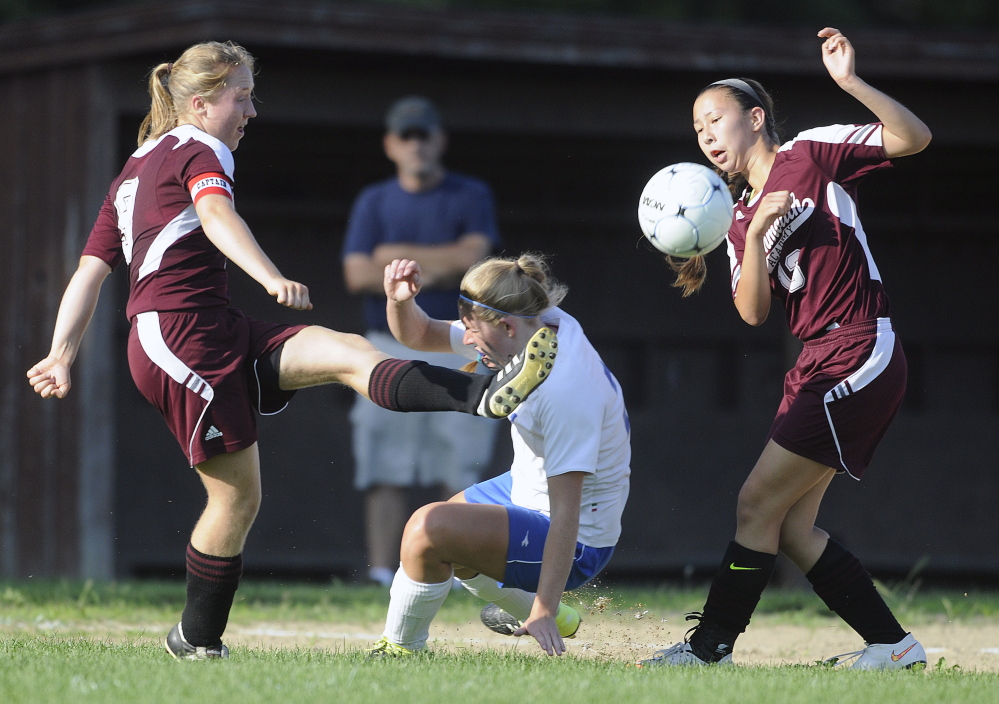 Staff photo by Andy Molloy 
 Monmouth Academy's Maddie Bumann, left, kicks the ball away from Oak Hill's Brittany Marquis toward Monmouth teammate Tia Day during a Mountain Valley Conference game Wednesday in Wales.