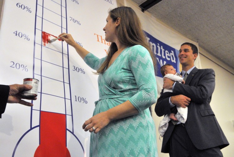 Campaign co-chairwoman Stephanie, Garofalo, left, paints in a thermometer showing they’re already at 51% of their goal as co-chairman Craig Garofalo watches with their son Weston during the United Way of Kennebec Valley kickoff breakfast on Thursday at the Augusta Civic Center.
