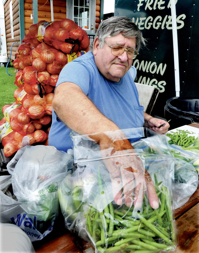 Glenn Tripp prepares vegetables at the J.H. Concessions blooming onion stand at the Clinton Lions Club fair on opening day Thursday. The fair runs through Sunday.