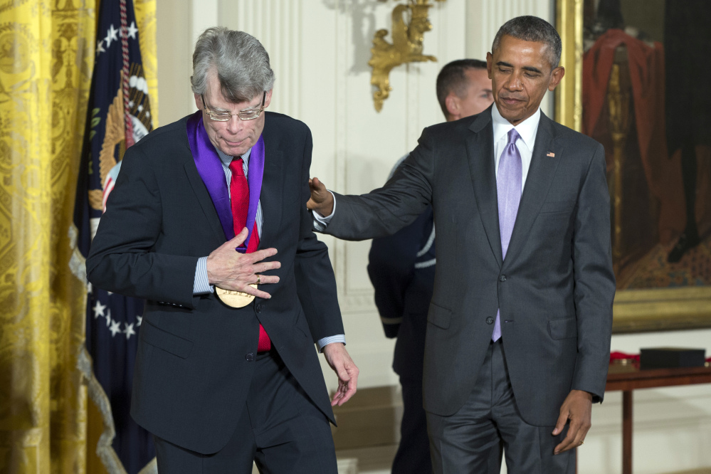 Author Stephen King, of Bangor, Maine, left, walks off stage after being presented with the 2014 National Medal of Arts medal by President Barack Obama during an event in the East Room of the White House, on Thursday, Sept. 10, 2015, in Washington.