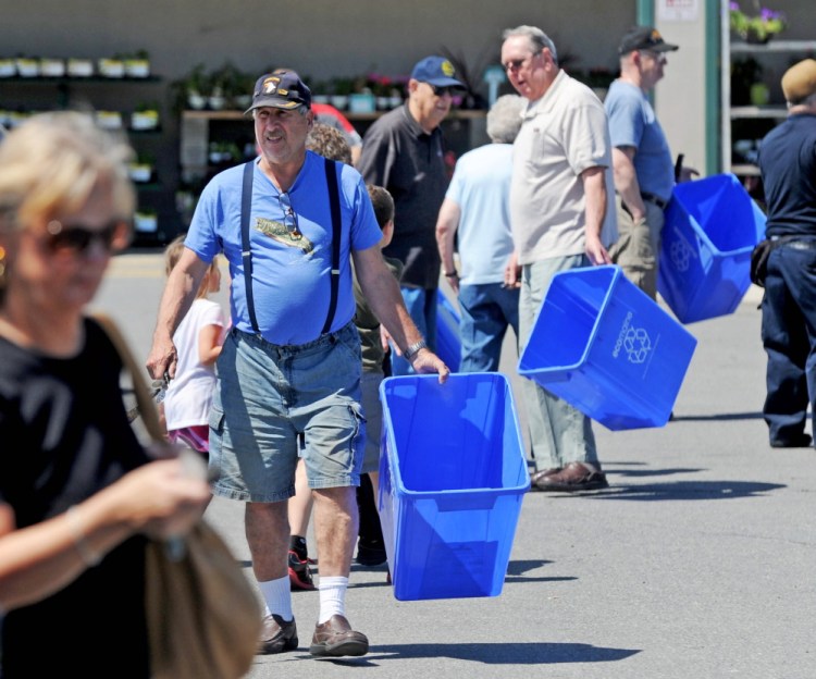 People make their way back to their vehicles with free recycling bins from Ecomaine at Elm Plaza in Waterville in June 2014. The program is part of the city’s pay-as-you throw trash program that began a year ago.