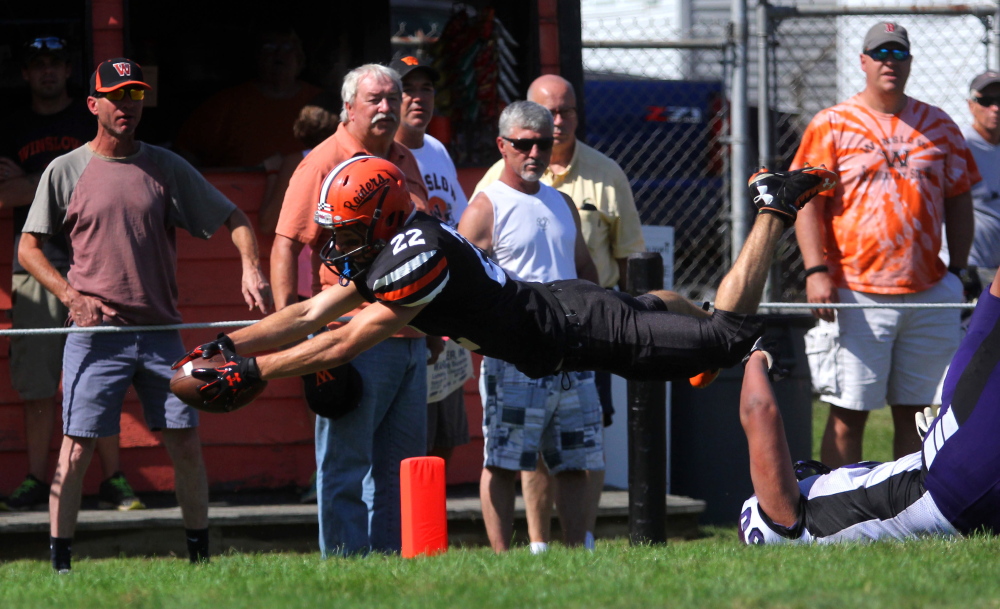 Photo by Jeff Pouland 
 Winlsow High School's Nate St. Amand dives over John Bapst defender Harrison Dieuveuil and into the end zone for a touchdown in the first half of a game against John Bapst at Poulin Field in Winslow on Saturday. Winslow won 63-0.