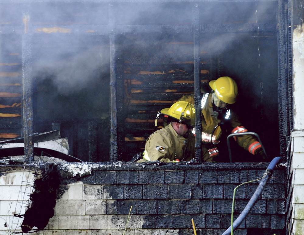 Firefighters can be seen putting out fire inside a home that was destroyed on Swan Hill Road in Oakland on Monday.