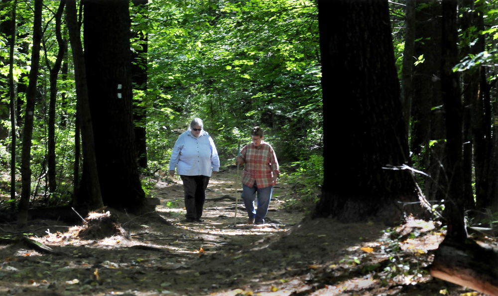Deborah Staber, left, director of the L.C. Bates Museum in Hinckley, and Melissa Bastien, walk along the Dartmouth Trail behind the museum on Monday. This Saturday is the 100th anniversary of the trail and officials hope 100 hikers show up to celebrate.
