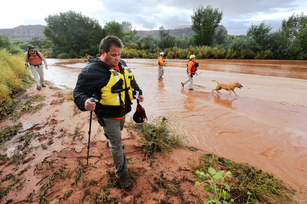 Members of the Mojave County search and rescue team use dogs to search for bodies after a flash flood Tuesday in Colorado City, Ariz.