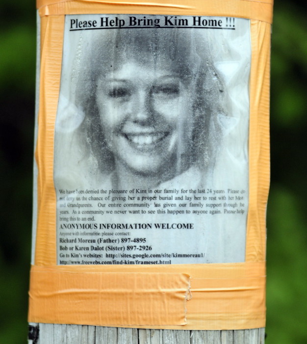A poster of Kimberly Moreau hangs on utility pole across street from a police search scene on Aug. 7 in Canton.