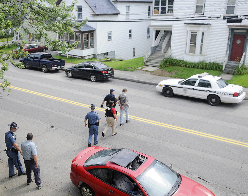 An Augusta Police detective, Maine State Police troopers and parole and probation officers escort a man arrested on outstanding warrants to a waiting cruiser on Northern Avenue in Augusta on July 30. State and county law enforcement officers accompanied Augusta police in door-to-door walks through several neighborhoods in Augusta as part of the city police department’s Operation Hot Spot program that