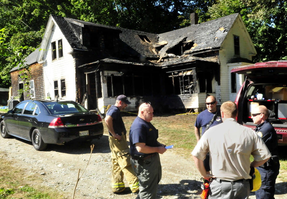 Oakland fire chief Dave Coughlin, left, listens as State Fire Marshal’s Office investigator Kenneth MacMaster speaks with other investigators including John Wardwell, second from right, and Jeremy Damren outside the fire damaged home on Swan Hill Road in Oakland on Tuesday to determine the cause of the Monday fire.