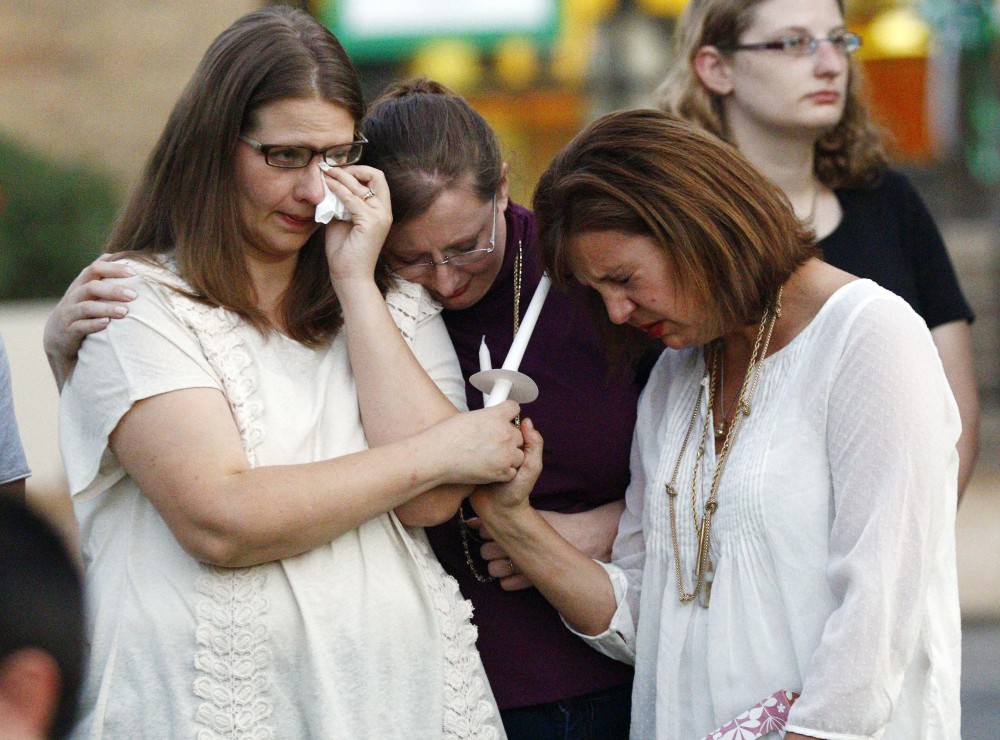 Liz Schmidt, widow of Delta State University history professor Ethan Schmidt, who was murdered by a colleague in his office Monday, left, is comforted by friends, Jenn Westmoreland, center and Amy Cotrell, prior to a candlelight memorial in his honor on the Cleveland, Miss., campus, Tuesday.