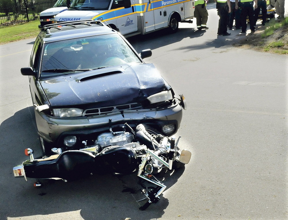 Ambulance personnel treat a seriously injured motorcycle operator May 19 after a collision with a vehicle on Grove Street in Waterville.