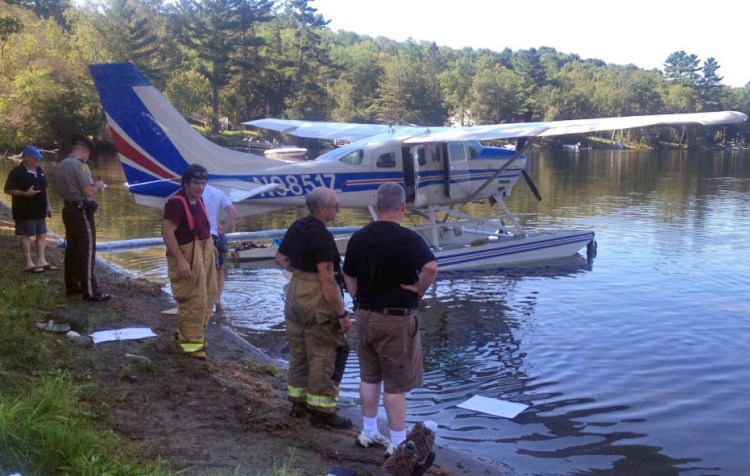Emergency responders gather around an airplane that made an emergency landing on Wesserunsett Lake Thursday morning. 