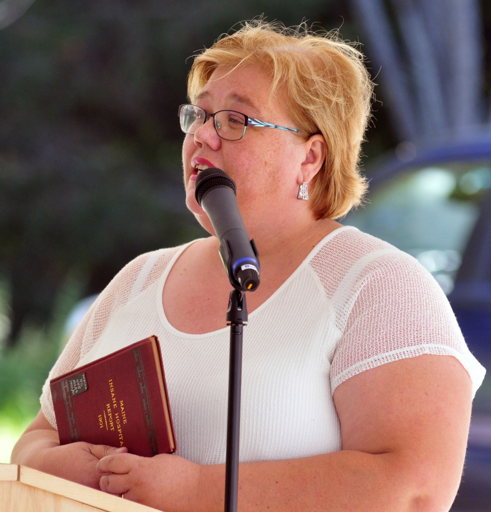 Simonne M. Maline, executive director of the Consumer Council System of Maine, holds a copy of a 1901 Maine Insane Hospital report as she speaks during a dedication of a marker Friday in memory of people who died at the former Augusta Mental Health Institute on Friday at Cony Cemetery in Augusta.