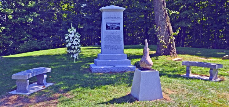 A stone sculpture of an eternal flame stands in front of the monument in honor of people who died at the former Augusta Mental Health Institute before a dedication Friday at Cony Cemetery in Augusta.
