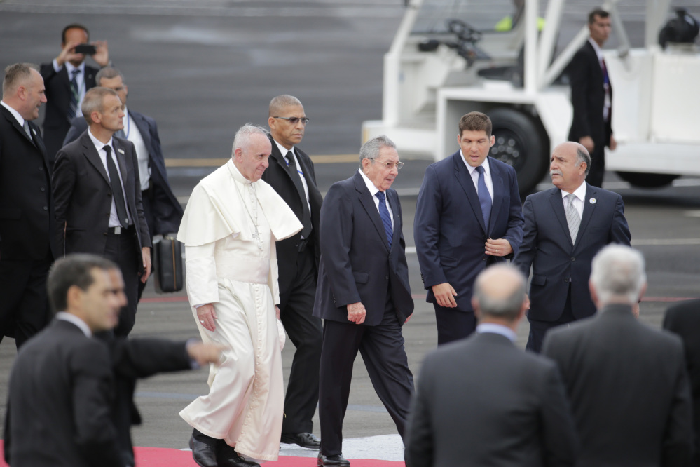 Surrounded by security, Pope Francis walks with Cuba’s President Raul Castro as he arrives to Havana, Cuba, Saturday.