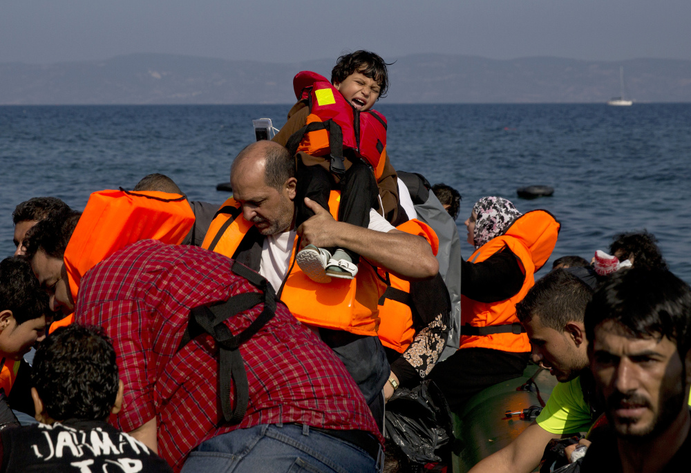 Migrants arrive aboard a dinghy after crossing from Turkey, to the island of Lesbos, Greece, on Sunday. A boat with 46 migrants or refugees has sunk Sunday in Greece and the coast guard says it is searching for 26 missing off the eastern Aegean island of Lesbos.