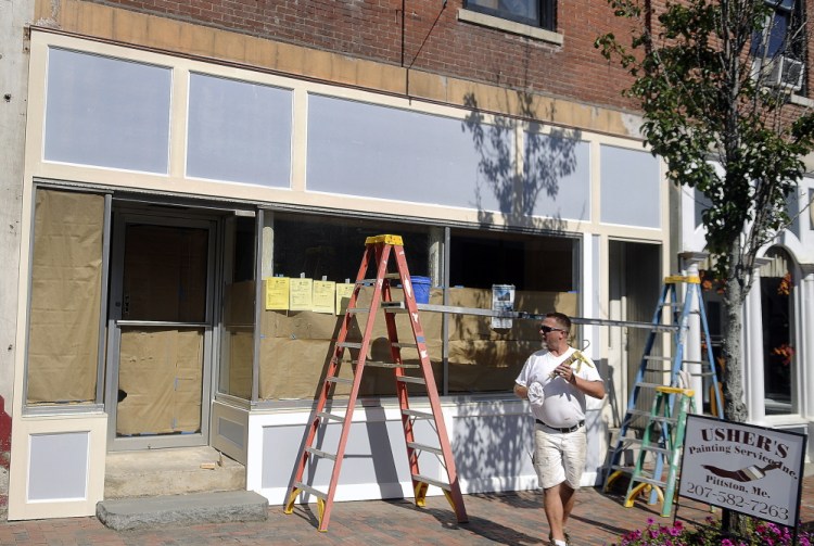 Derek Usher prepares to caulk the exterior of the building last week that will serve the Craft Beer Cellar Gardiner franchise on Water Street in Gardiner.