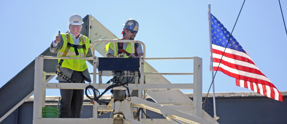 Charles “Wick” Johnson, left, gives a thumbs up Monday after bolting a beam with ironworker Chris Cochran at the peak of the Lithgow Public Library in Augusta during a topping off ceremony.