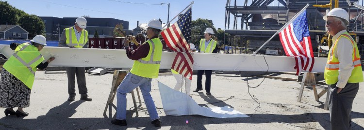 People sign an iron beam before it was placed at the peak of the addition Monday at Lithgow Public Library in Augusta during a topping off ceremony.