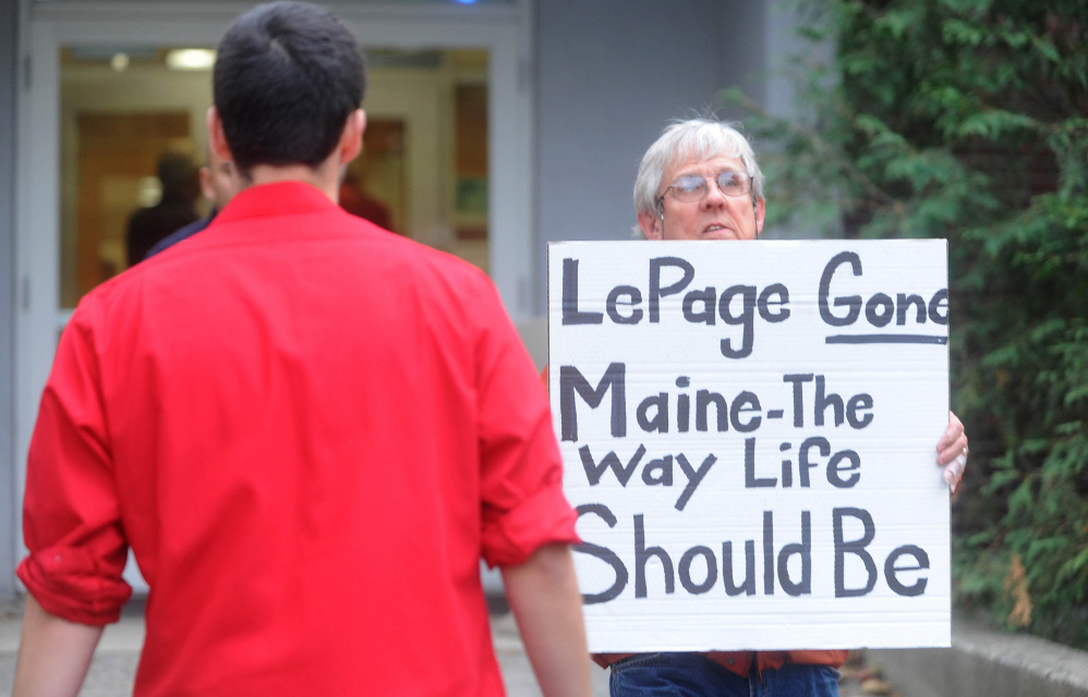 A protester leaves Preble Hall on Tuesday after showing his sign in opposition to Gov. Paul LePage before the governor took questions and delivered remarks to residents about his plan to move Maine forward at Thomas Auditorium at Preble Hall at the University of Maine at Farmington.