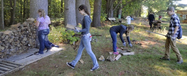 Maranacook Community High School juniors stack firewood Wednesday at the former Elizabeth Arden Estate, which is being renovated by the Travis Mills Foundation in Rome into a retreat for wounded veterans.
