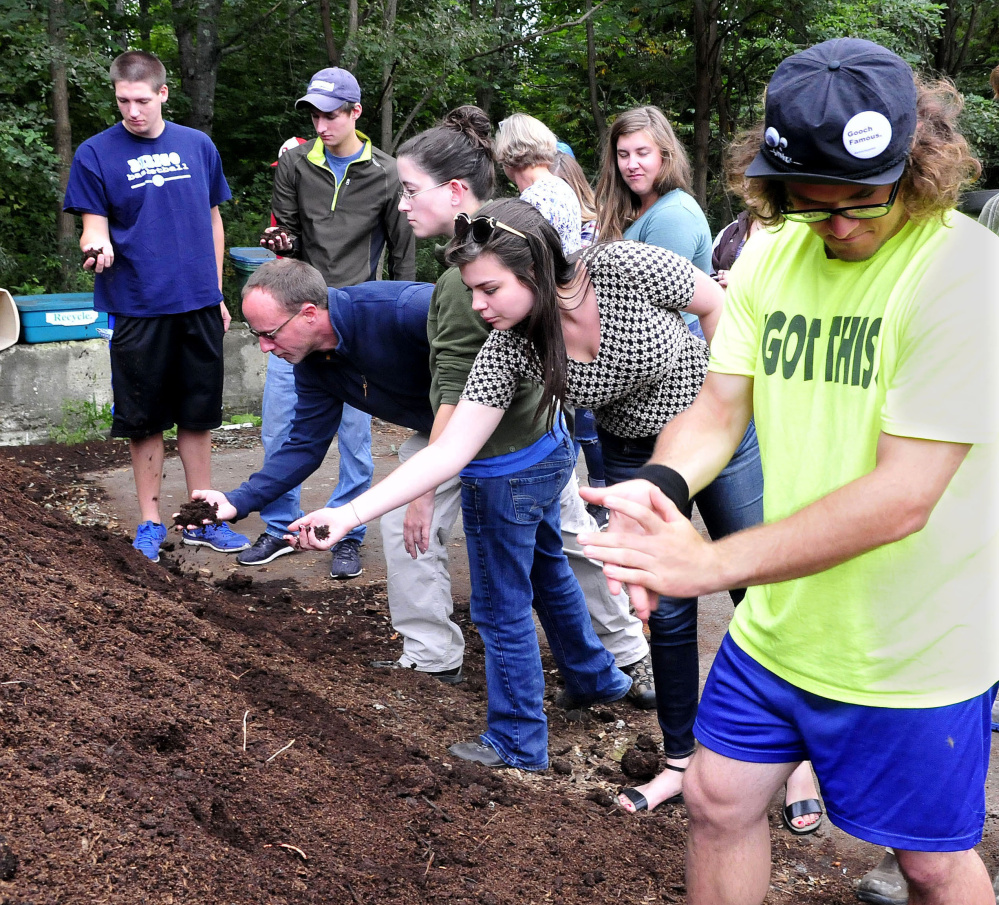 University of Maine in Farmington students feel and smell compost material made from food and farm waste at the Farmington Compost Cooperative site on Tuesday. Student Glenn Lumbert, right, claps the material off his hands.