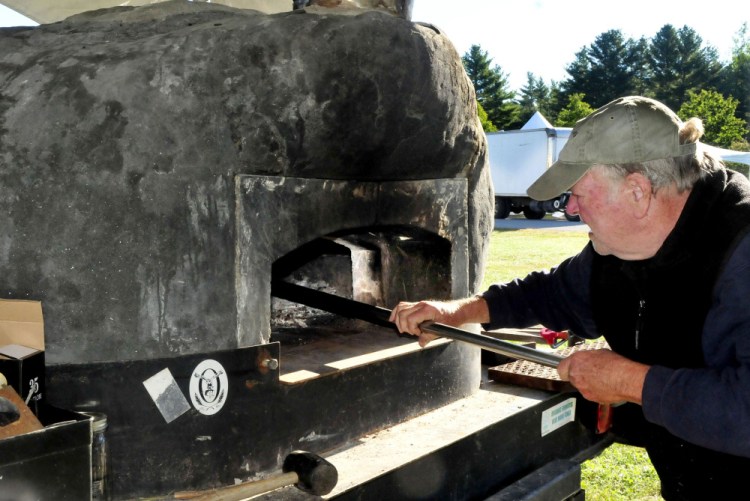 Vince Collins of Harvest Moon Pizza prepares to light a wood-fired oven while getting ready in the food court area of the Common Ground Country Fair site in Unity on Wednesday. The 39th annual fair begins Friday.