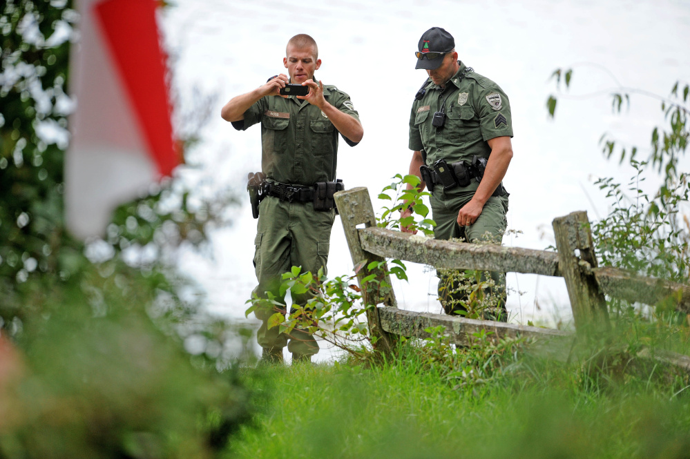 Maine wardens stand on the shoreline of Lovejoy Pond in Albion on Friday after a man died while fishing from a canoe with his father. 