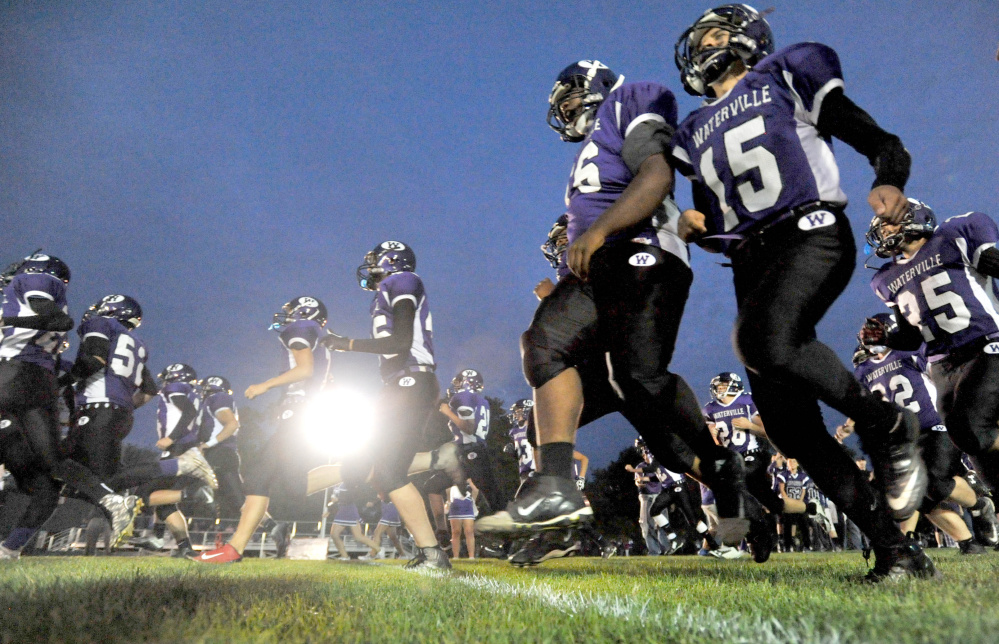 Members of the Waterville Senior High School football team run onto Drummond Field prior to a Big Ten Conference game Friday night against Oceanside. It marked the first night game in program history at Drummond Field.