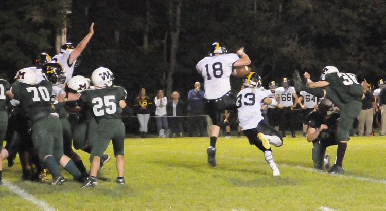 Staff photo by Joe Phelan 
 Maranacook's Jake Gibson (18) and Zach Lacasse block an extra point attempt by Winthrop/Monmouth kicker Tyler Cote during a game Friday night at Maxwell Field in Winthrop.