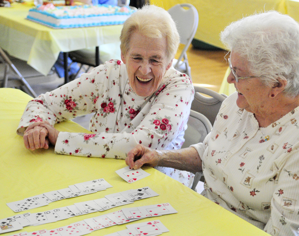 Joyce Pinkham, left, and Dorothy Wallace laugh as they play cards Saturday during a 10th-anniversary party for the Golden Oldies Senior Center in Richmond.