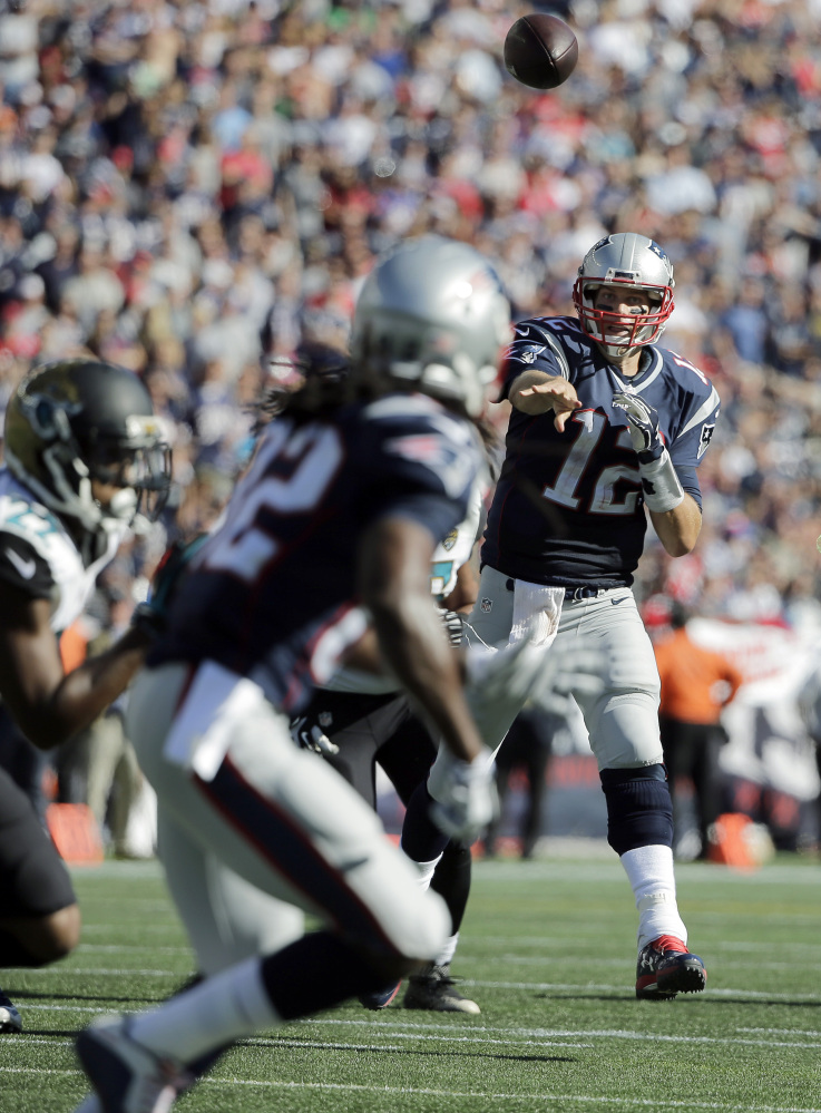 New England Patriots quarterback Tom Brady (12) throws a touchdown pass to wide receiver Keshawn Martin, foreground, in the second half against the Jacksonville Jaguarson Sunday, in Foxborough, Mass.
