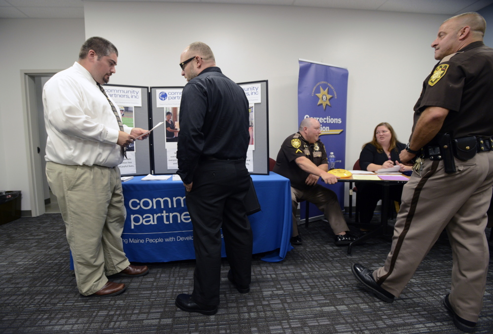 Steven Cay, left, a recruiter with Community Partners Inc., speaks with Matthew Ferrante, center, of South Portland during Wednesday's job fair at the Greater Portland CareerCenter.