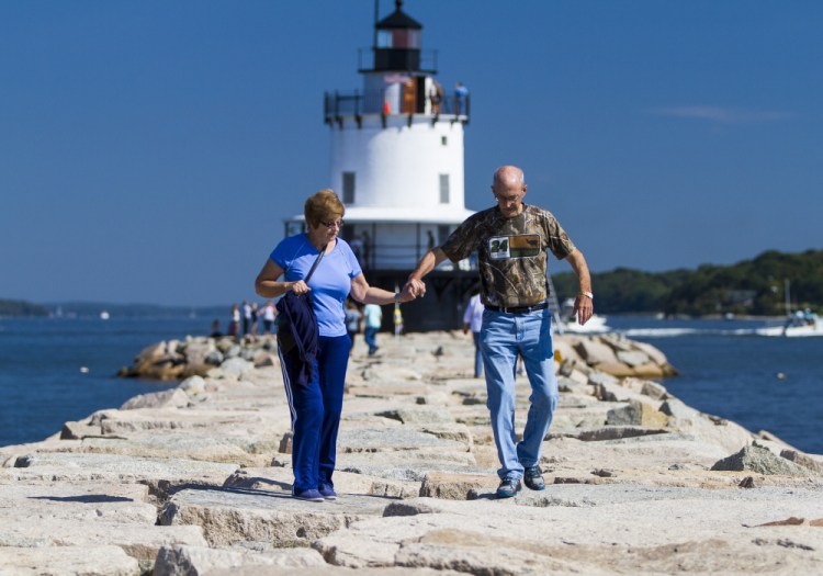 Marie and Douglas Pyle of Lewisville, Texas, stroll along the 950-foot breakwater that leads to Spring Point Ledge Lighthouse in South Portland during Maine Open Lighthouse Day on Saturday. Visitors say lighthouses are must-see icons of Maine.