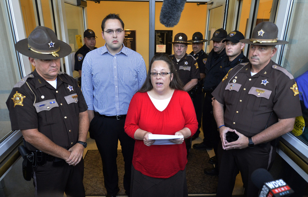 Surrounded by Rowan County Sheriff’s deputies, Rowan County Clerk Kim Davis, center, with her son Nathan Davis standing by her side, makes a statement to the media at the front door of the Rowan County Judicial Center in Morehead, Ky., Monday.