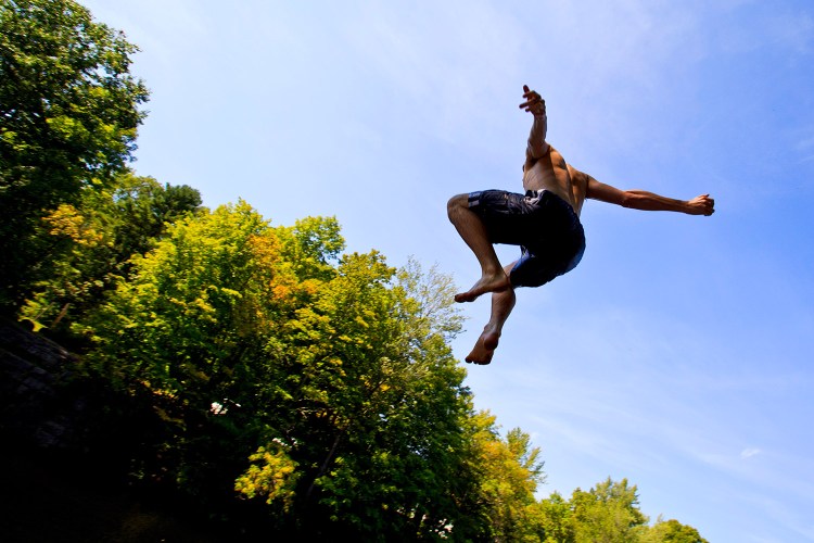 John Vedral, 17, of Buxton, jumps off a rock face into the Saco River in Buxton on Wednesday. He and a group of fellow Bonny Eagle High School students went swimming to cool off after they were dismissed early because of dangerously warm classrooms as  outside temperatures climbed into the 90s. 