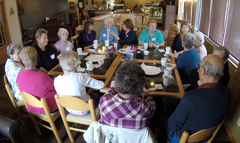 A group of people with dementia, their caregivers and officials from a local nursing home talk, drink coffee and eat cookies at Connections Cafe in Watertown, Wis., in May. The support and social group called "Memory Cafe" is part of the city's efforts to become a dementia friendly city. The Associated Press